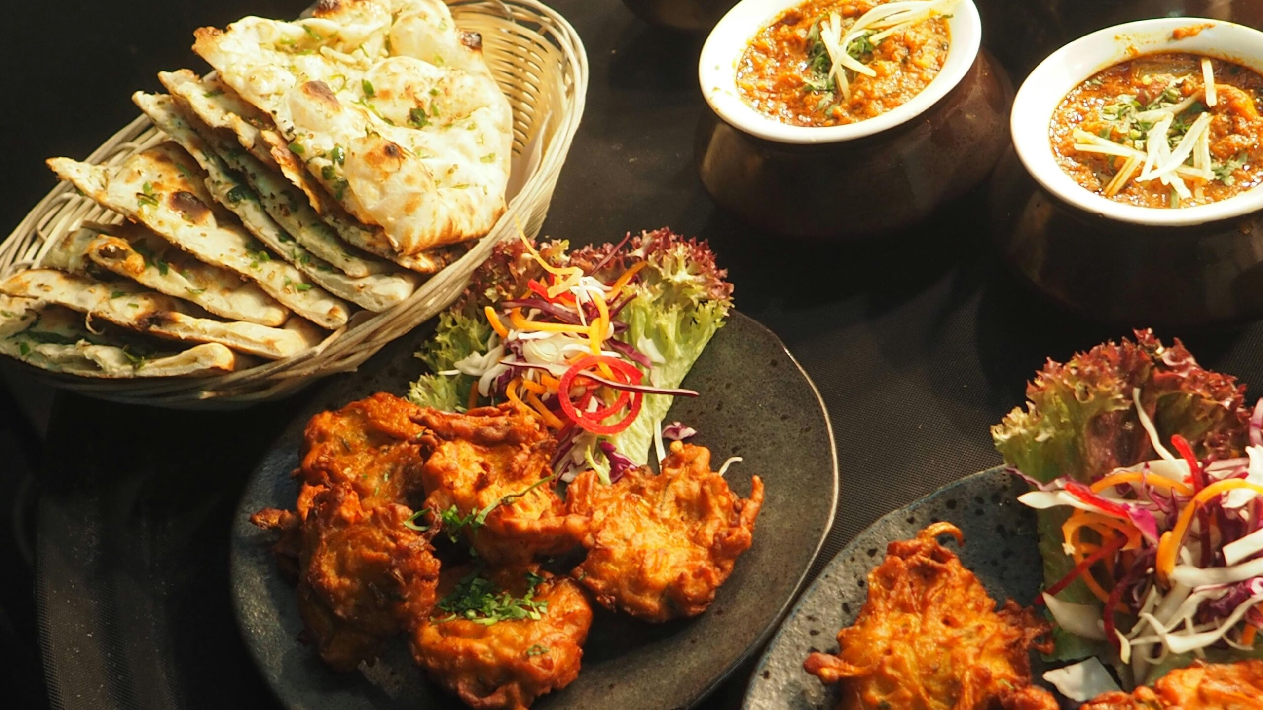 A delicious Indian food spread featuring curries, naan, and colorful salads, perfect for dinner.