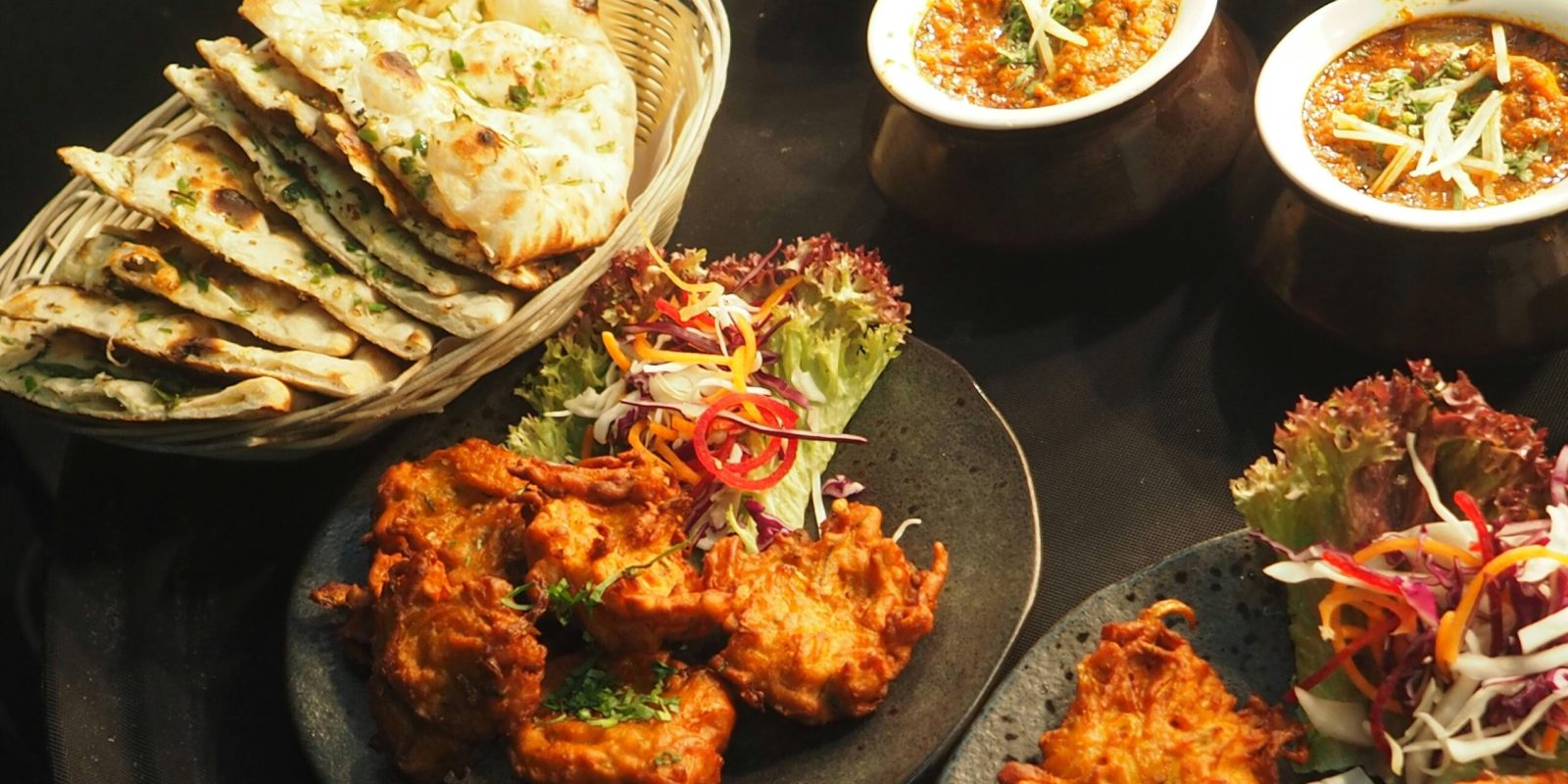 A delicious Indian food spread featuring curries, naan, and colorful salads, perfect for dinner.